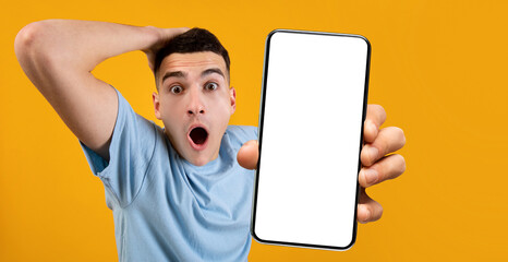 Aufkleber - Wow, Super Huge Discount. Portrait of shocked guy grabbing head holding smartphone with white empty screen in hand, showing device close to camera, orange studio. Gadget display with copyspace, mockup