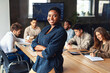 © Prostock-studio - Modern entrepreneur concept. African american businesswoman standing with folded arms in conference room during meeting with colleagues and smiling at camera