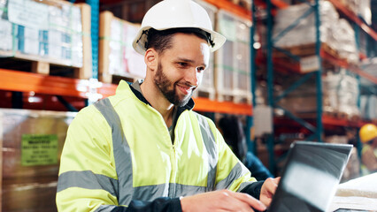Poster - Man, laptop and typing for distribution at warehouse with review for order, smile and inventory management. Person, computer and scroll for shipping, logistics and supply chain at industrial plant