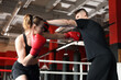 © New Africa - Woman in protective gloves having boxing practice with her coach at training center