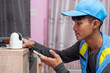 © suwanb - Asian male technician installs and sets up CCTV or wireless security cameras using smartphone at customer's home