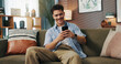 © peopleimages.com - Texting, smile and man with phone in home for communication, chat and reading message. Sofa, relax and happy person with mobile for social media, online dating and browsing website to download app
