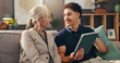 © peopleimages.com - Senior woman, nurse and tablet on couch, happy and report for wellness in living room at apartment. Caregiver, elderly person and digital touchscreen for health, application and results in retirement