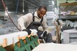 © Serhii - African american Furniture maker assembling sofa in factory