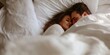 © MNStudio - Young loving couple cuddling in bed in the morning. Young man and woman hugging laying on white sheets. Husband and wife in love.
