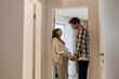 © Drobot Dean - Pregnant woman and man standing and smiling while holding hands, in the hallway between rooms