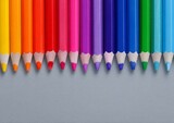 A childhood creative art concept is illustrated by colored pencils positioned on a gray background, complete with an empty area for inserting text or creating drawings