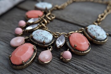 Poster - Elegant necklace with coral and stone elements displayed on wooden surface in natural light