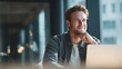 © Evodigger - Confident businessman sits at desk working with laptop in office,smiling,business concept.