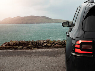 Wall Mural - Black car parked with view on amazing nature scene with ocean, mountain, and cloudy sky. Dingle peninsula, Ireland. Popular travel area with stunning Irish landscape. Nobody.