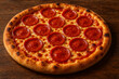 © Tilan - Whole Pepperoni Pizza with Melted Cheese on a Wooden Table