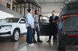© Serhii - Car salesman showing new vehicle to african american couple in dealership