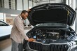 © Serhii - Customer examining car engine in dealership before purchase