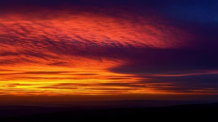 Wall Mural - Vibrant sunrise sky featuring layered clouds with vivid reds, oranges, yellows, and hints of blue at the horizon.