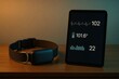 © HannaStudio - Smartwatch and tablet displaying health metrics on wooden table, dim lighting.