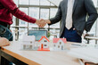 © Kritdanai - Real Estate Deal Handshake with House Models