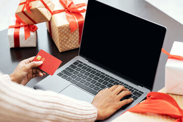 Poster - Online Holiday Shopping. Over the shoulder view of african american woman holding red credit card and using computer with black blank screen for mockup template, female buyer ordering presents