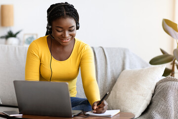 Aufkleber - Online Education Concept. Smiling Black Woman In Headset Studying With Laptop At Home And Taking Notes To Notepad, Enjoying Distance Learning, Watching Webinar In Internet And Noting Highlights