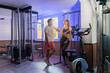 © de Art - Couple working out in home gym, Personal trainer assisting client