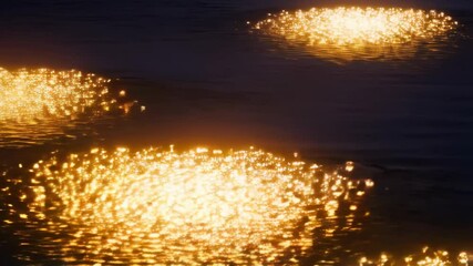Poster - Golden glittering lights reflecting on dark ripples of water, creating shimmering and textured surface patterns at dusk or night