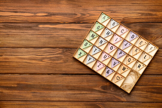 Alphabet in wooden box on wooden background. Top view