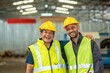 © BESTIMAGE - Two happy factory workers wearing hard hats and safety vests standing with arms crossed.