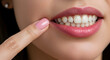 © abu - Close Up of Woman's Face Featuring Healthy White Teeth Pink Lipstick and Nail Polish with Finger Pointing at Mouth