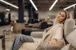 © Roman - Relaxed Woman Sitting Comfortably on a Sofa in a Modern Furniture Store