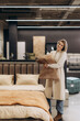 © Roman - Smiling Woman Shopping for Pillows in a Modern Bedroom Furniture Store