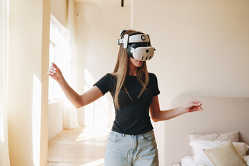 Poster - Woman engages in virtual reality experience indoors while wearing a headset during daylight hours