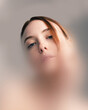 © Lustre Art Group  - Conceptual artwork. Portrait of red-haired woman with piercing blue eyes looking downwards through blurred filter, conveying isolation and introspection. Concept of beauty, psychology.