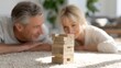 © t.sableaux - A couple plays Jenga on a cozy rug in a bright living room, filled with suspense and joy, kidults concept, kidults concept