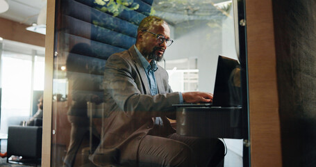 Poster - Businessman, laptop and thinking in office for communication, planning and privacy cubicle. Hybrid work, networking and technology with employee in pod for mobile negotiation, research or update
