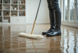 © Pungkas - Person wearing black rubber boots cleaning water flooded indoor floor with mop in modern room