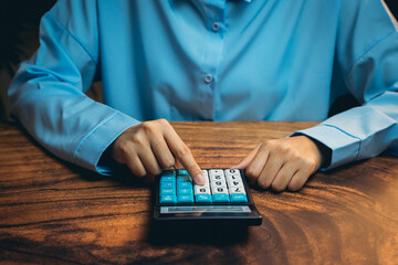 Poster - Person in Blue Shirt Using Calculator on Wooden Table for Financial Calculation and Business Planning