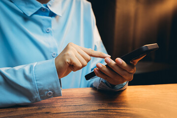 Poster - Hands of a Person Interacting with a Mobile Device on a Wooden Surface in a Dimly Lit Environment