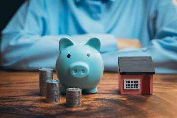 Poster - Blue Piggy Bank with Coins and Miniature House on Wooden Table for Financial Planning and Investment Concepts
