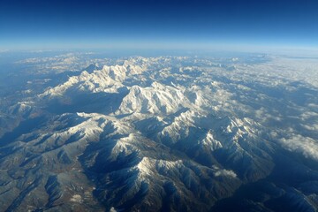 Poster - Snow-capped mountain range under clear blue sky with gentle clouds, offering a breathtaking aerial view of nature's beauty