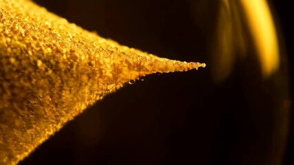 Poster - Extreme close-up of a bright yellow textured surface with tiny bumps and a sharp point against a dark backdrop with blurred glowing bokeh.