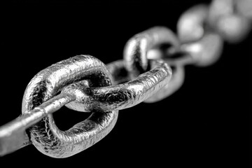 Aufkleber - Close-up view of a metallic chain link showcasing texture and shine against a dark background