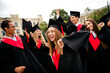 © deagreez - Young graduates celebrating success with joyful expressions on a sunny day at campus outdoors
