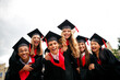 © deagreez - Joyous group of graduates in caps and gowns celebrating outdoors on a summer day