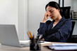 © sabthai - Young business woman touches her forehead to indicate stress or headache