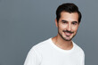 © SHOTPRIME STUDIO - Smiling man in casual white t-shirt poses confidently against a grey background, showcasing a friendly expression and engaging demeanor. Portrait photography concept.