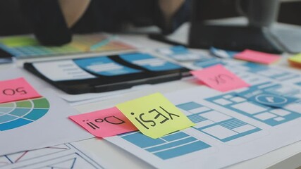 UX/UI designer working on wireframes for a website and mobile app prototype, surrounded by sketches of user-flow and design tools, in concept of website and mobile application design concept.