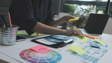 UX/UI designer working on wireframes for a website and mobile app prototype, surrounded by sketches of user-flow and design tools, in concept of website and mobile application design concept.