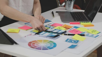 UX/UI designer working on wireframes for a website and mobile app prototype, surrounded by sketches of user-flow and design tools, in concept of website and mobile application design concept.