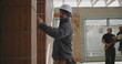 © Marco - Construction worker measuring wall with pencil, focused builder in safety helmet working indoors on brick structure, precision and attention to detail in construction