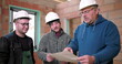 © Marco - Team of builders reviewing blueprints together indoors, construction planning, three men with safety helmets engaged in discussion about building project in unfinished structure