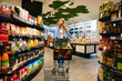 © Valerii Apetroaiei - Young woman shopping with cart full of groceries in supermarket aisle